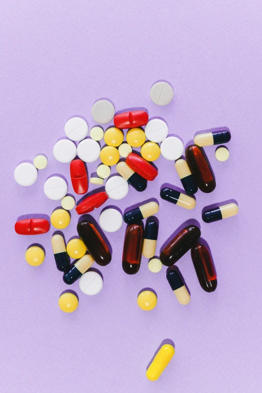 a pile of pills and capsules on a purple surface, by Nina Hamnett, antipodeans, black and yellow and red scheme, surgical supplies, multiple stories, abcdefghijklmnopqrstuvwxyz