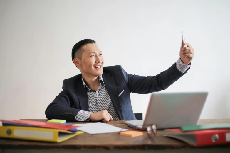 a man sitting at a desk with a cell phone in his hand, by Jang Seung-eop, pexels contest winner, taking a selfie, professional profile picture, ernie chan, confident pose