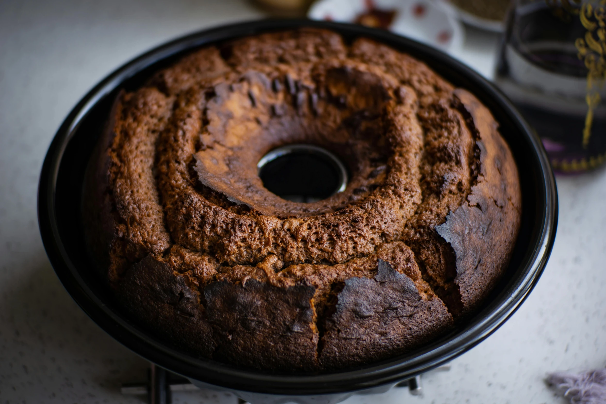 a close up of a cake in a pan on a table, by Simon Gaon, pexels contest winner, hurufiyya, symmetrical front view, “ iron bark, blender donut, well preserved