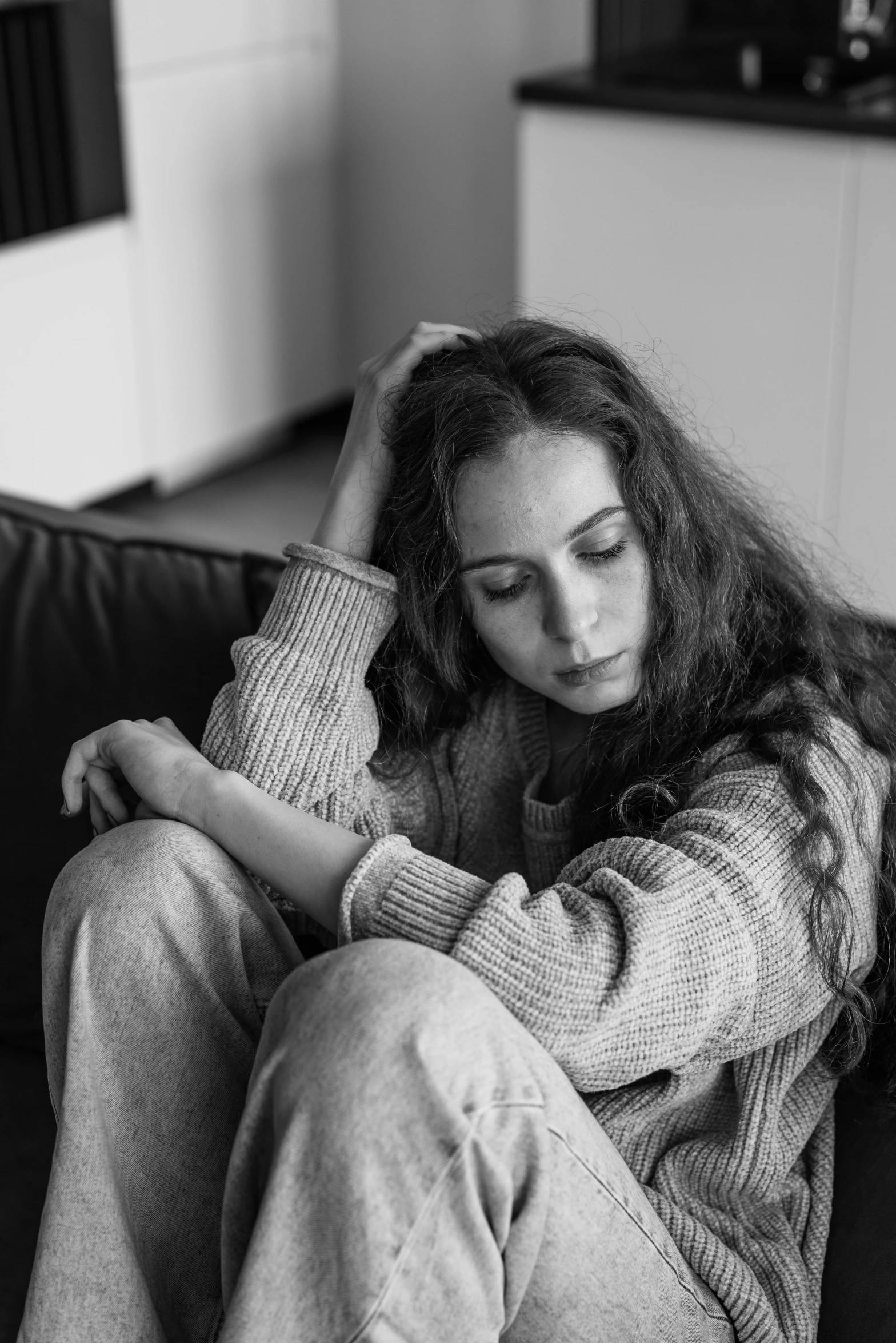 a black and white photo of a woman sitting on a couch, pexels, portrait of depressed teen, wavy hair spread out, 15081959 21121991 01012000 4k, hugging her knees