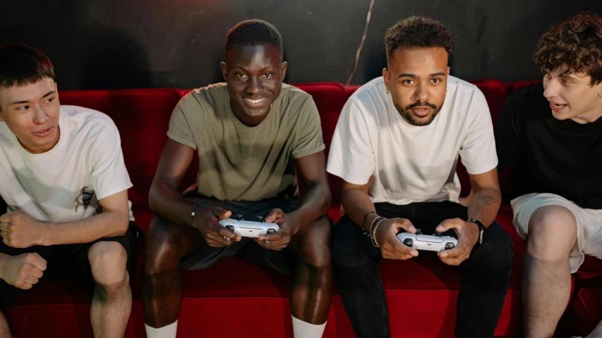 a group of young men sitting on top of a red couch, pexels, realism, holding controller, black man, nvidia promotional image, sport