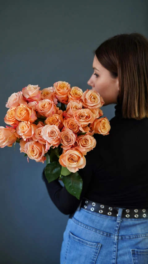 a woman holding a bouquet of orange roses, from the side, dark grey and orange colours, no cropping, award winning