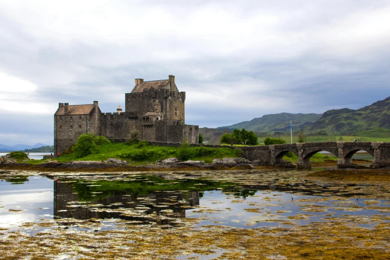 a castle sitting on top of a lush green hillside, a photo, inspired by Dugald Sutherland MacColl, pexels contest winner, building along a river, kilart, rustic, conde nast traveler photo