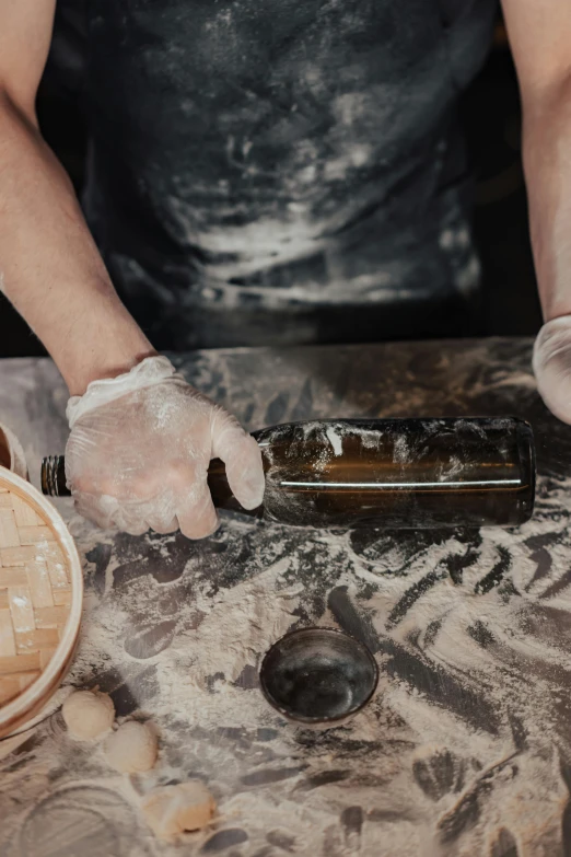 a person holding a bottle on top of a table, baking artwork, churning, carving, wine bottle