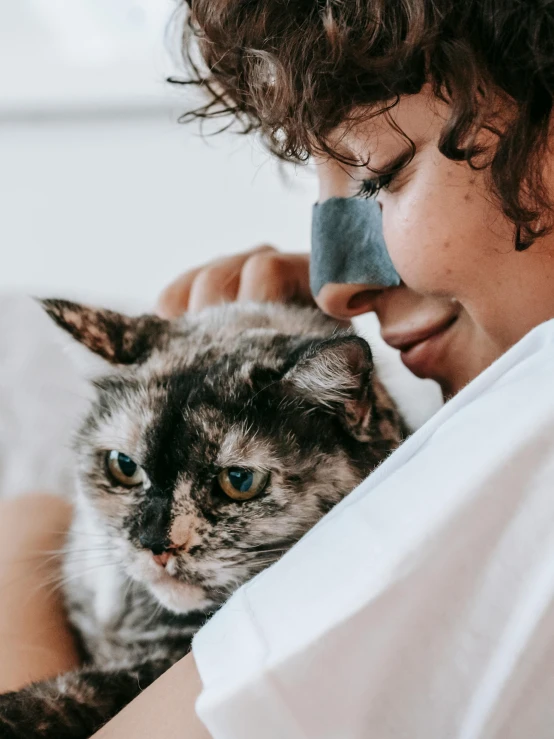 a close up of a person holding a cat, beauty mark on cheek, profile image, taken in 2 0 2 0, lazy eye