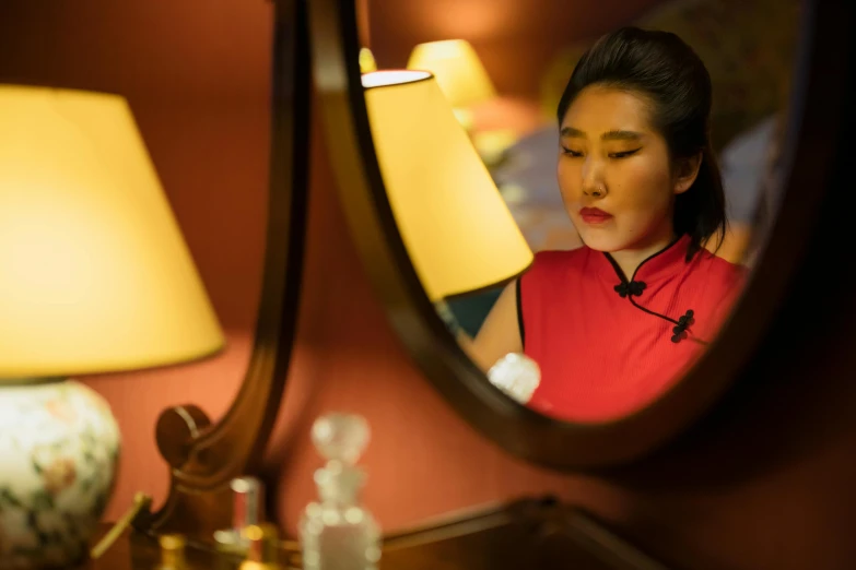 a woman looking at her reflection in a mirror, inspired by Min Zhen, red and cinematic lighting, hotel room, avatar image, chinese heritage