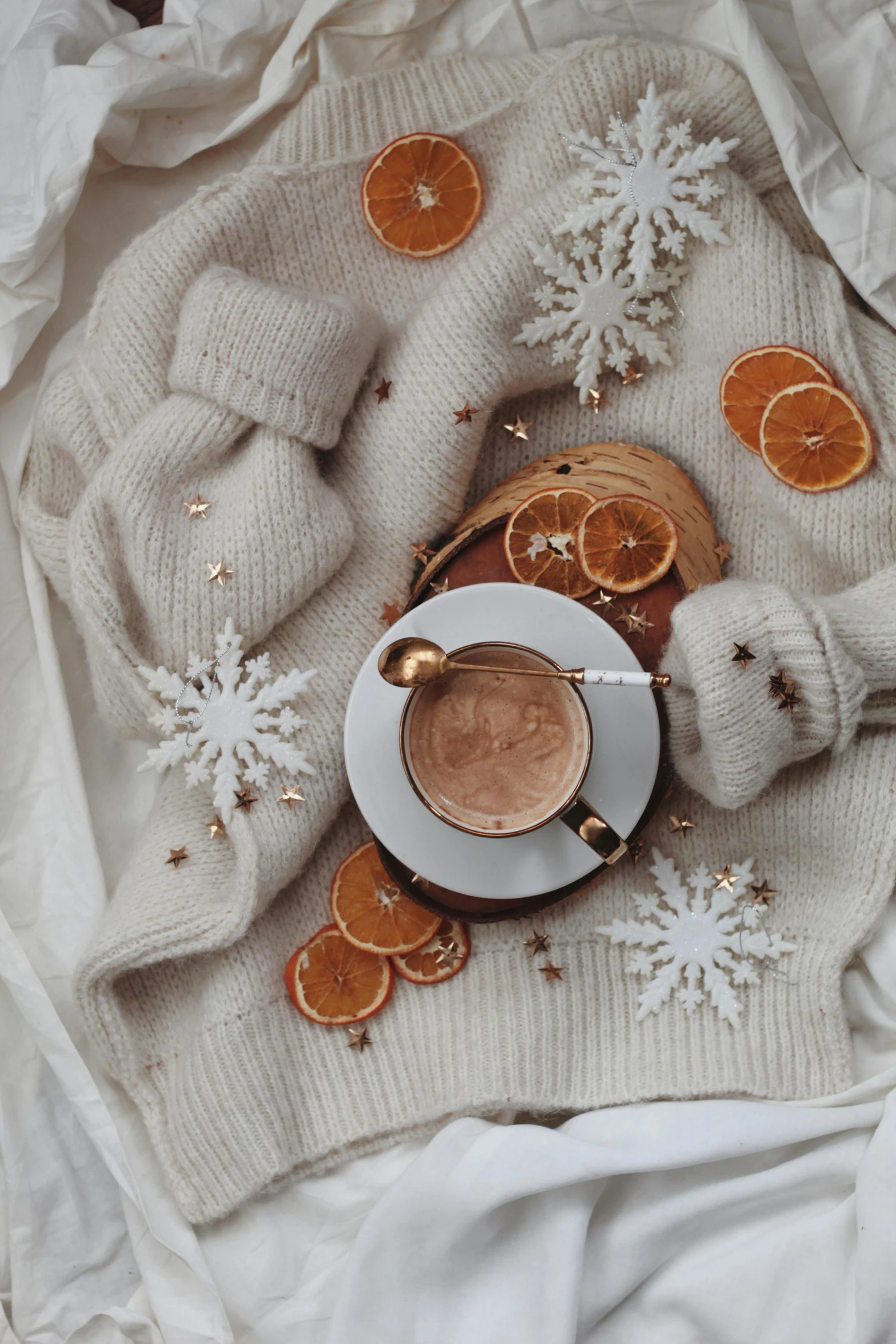 a cup of coffee sitting on top of a white blanket, a still life, by Lucia Peka, trending on pexels, baroque, snowflakes, grey orange, made of wool, twas brillig