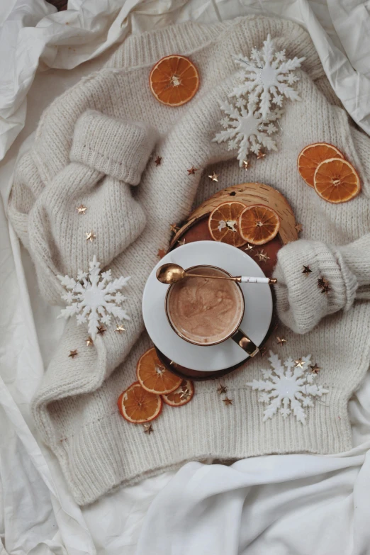 a cup of coffee sitting on top of a white blanket, a still life, by Lucia Peka, trending on pexels, baroque, snowflakes, grey orange, made of wool, twas brillig