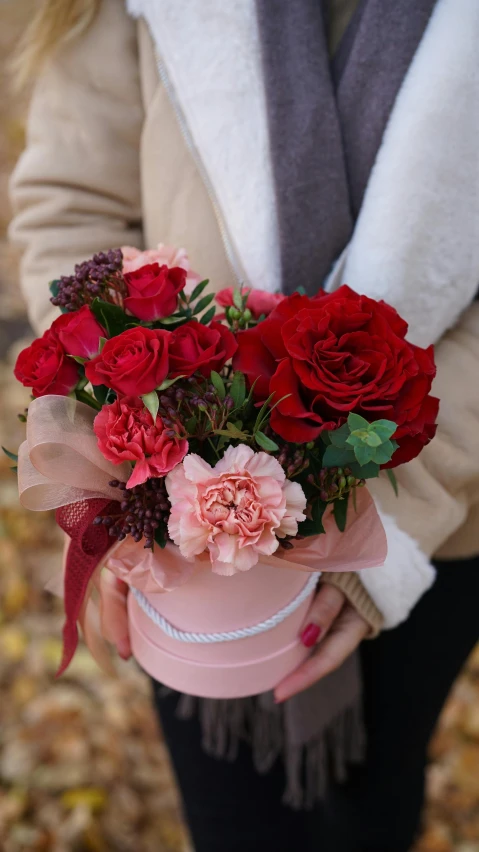 a woman holding a bouquet of red and pink flowers, designed for cozy aesthetics!, close look, holding gift, medium