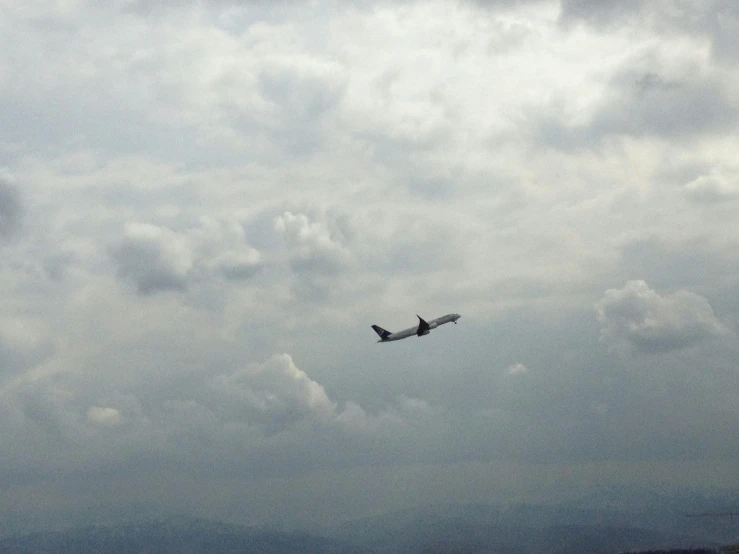 a large jetliner flying through a cloudy sky, a picture, pexels contest winner, hurufiyya, low quality footage, tourist photo, viewed from very far away, 2000s photo