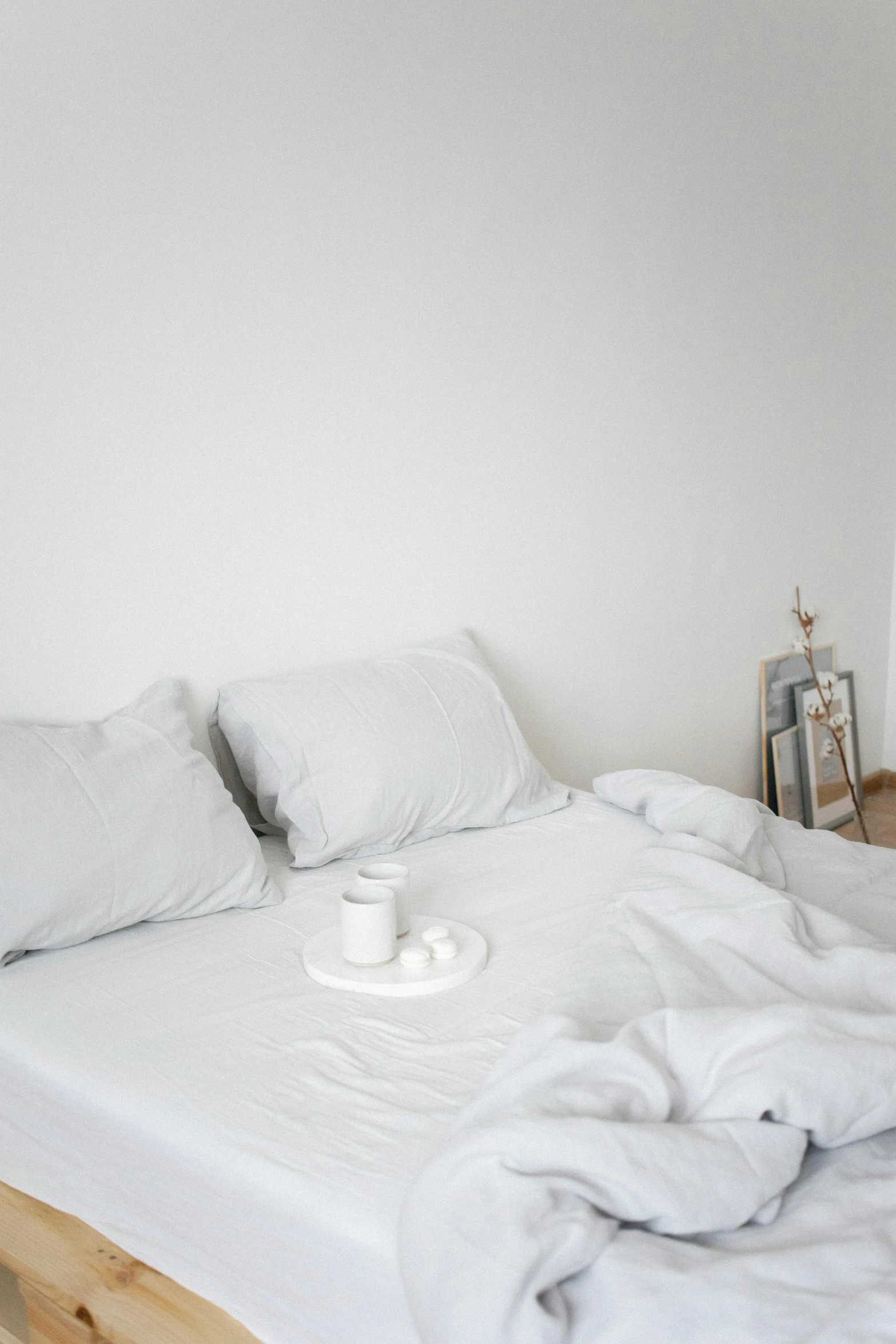 a white bed sitting in a bedroom next to a window, pexels contest winner, minimalism, white mug, grey clothes, low quality photo, food