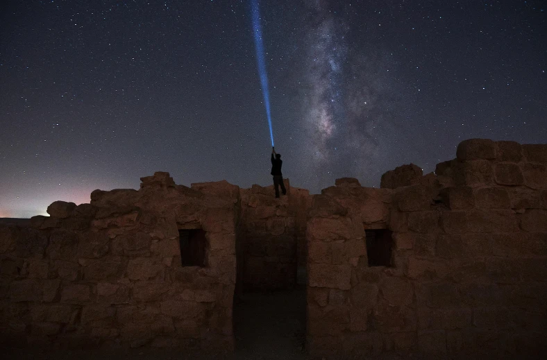 a person standing on top of a building under a sky full of stars, at the stone ruins, blue light saber, photo from the dig site, rim light and highlights