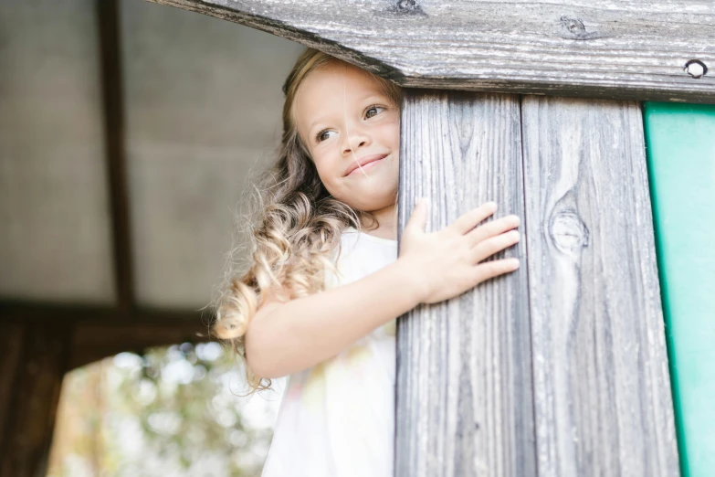 a little girl standing next to a wooden structure, portrait image, 15081959 21121991 01012000 4k, hugging, opening door