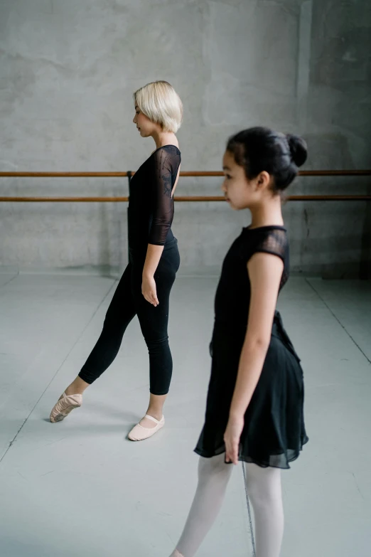 a couple of women that are standing in a room, by Elizabeth Durack, trending on unsplash, arabesque, ballet dancer, child, avant designer uniform, black