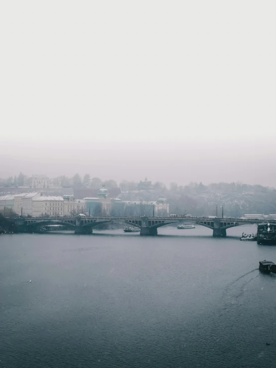 a large body of water with a bridge in the background, by Adam Szentpétery, gloomy and foggy atmosphere, prague in the background, low quality photo, a high angle shot