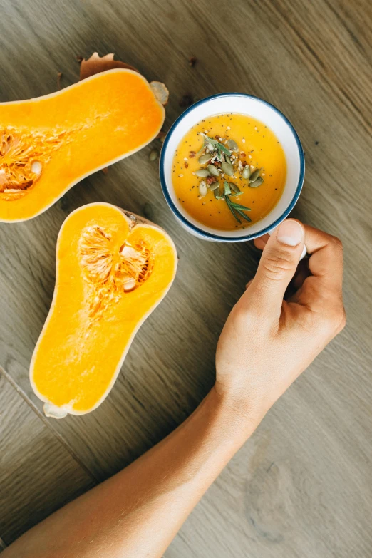 a close up of a person holding a bowl of soup, pumpkin, flatlay, no - text no - logo, mango