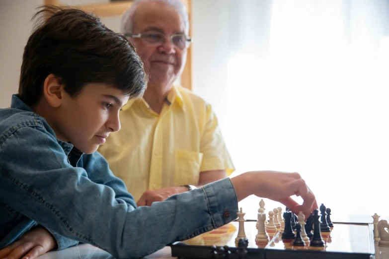 a young boy playing a game of chess with an older man, by Adam Marczyński, pexels contest winner, 15081959 21121991 01012000 4k, thumbnail, looking to his left, over his shoulder