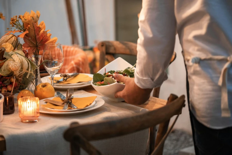 a person standing at a table with a plate of food, pexels contest winner, renaissance, late summer evening, place setting, linen, blending