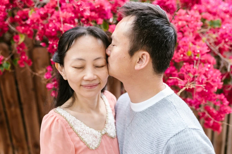 a man and a woman standing next to each other, a picture, inspired by Cui Bai, pexels contest winner, happening, flowers on heir cheeks, family friendly, kissing, asian male