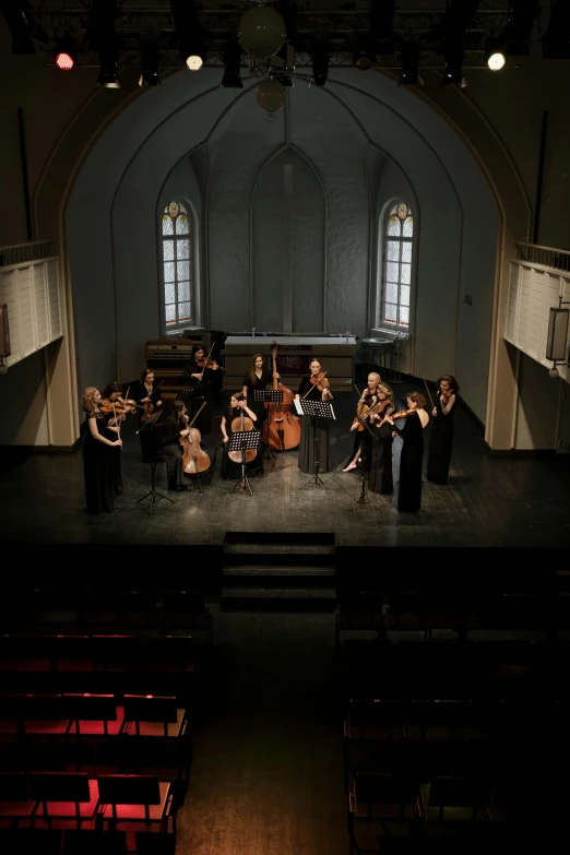 a group of people standing on top of a stage, an album cover, by Jakob Emanuel Handmann, baroque, strings, wide aerial shot, scene set in a church, a long-shot from front