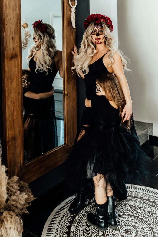 a woman in a black dress standing in front of a mirror, with a kid, long flowy hair, wearing a tutu, flatlay