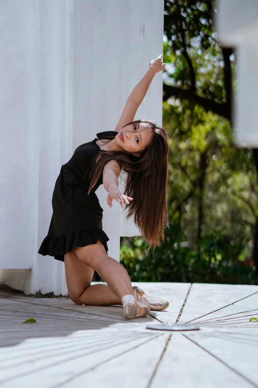 a woman kneeling on the ground in front of a building, by Robbie Trevino, arabesque, doing a sassy pose, profile image, 2 0 yo, performing