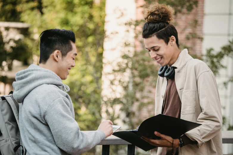 a couple of people standing next to each other, pexels contest winner, academic art, writing on a clipboard, asian male, lachlan bailey, smiling at each other