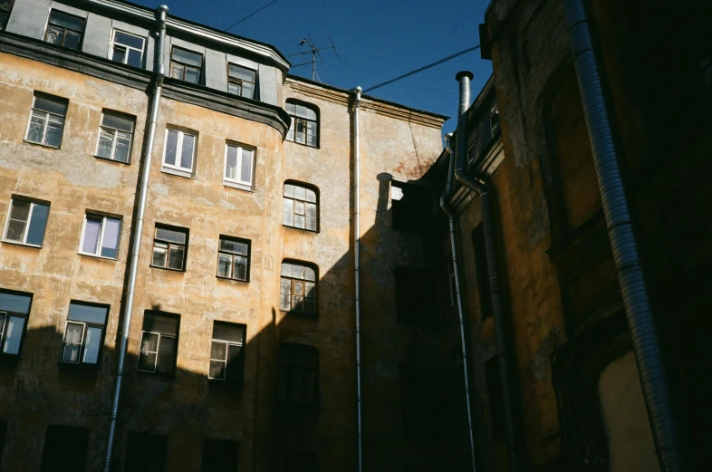 a couple of buildings that are next to each other, inspired by Elsa Bleda, pexels contest winner, neoclassicism, harsh sun light, tenement buildings, great light and shadows”, russian architecture