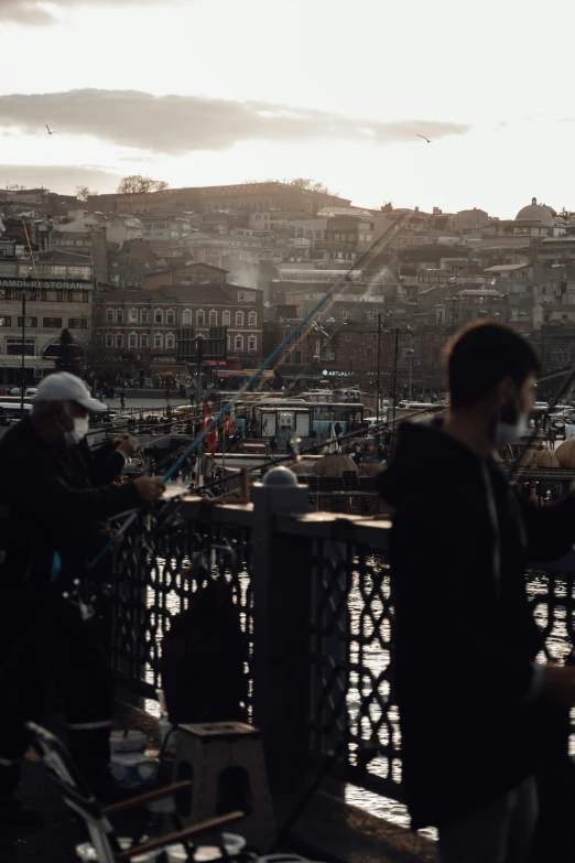 a group of people standing on top of a bridge, istanbul, fishing town, unsplash photography, brown