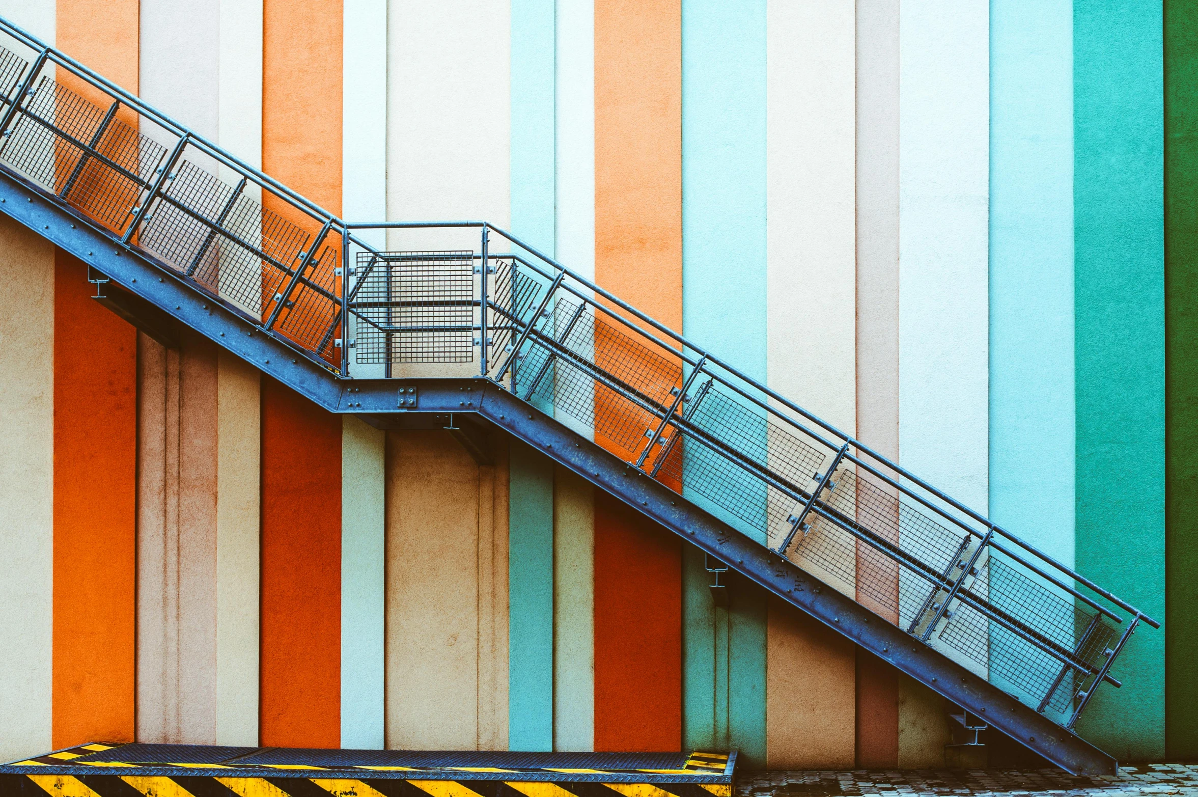 a set of stairs going up the side of a building, inspired by Bauhaus, pexels contest winner, striped orange and teal, industrial colours, multicolor, cold colours