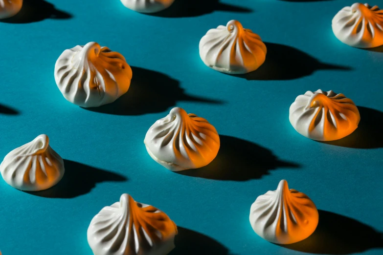 a group of meringue sitting on top of a blue surface, by Sylvia Wishart, trending on unsplash, surrealism, raytracing shadows, steamed buns, thumbnail, intricate art deco pasta designs