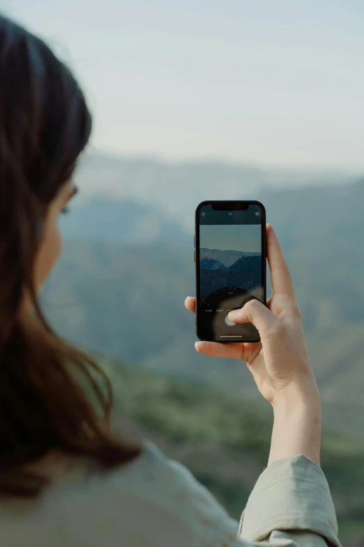 a woman taking a picture with her cell phone, trending on unsplash, video art, mountain scape. film still, 8k hd resolution”, back, on display