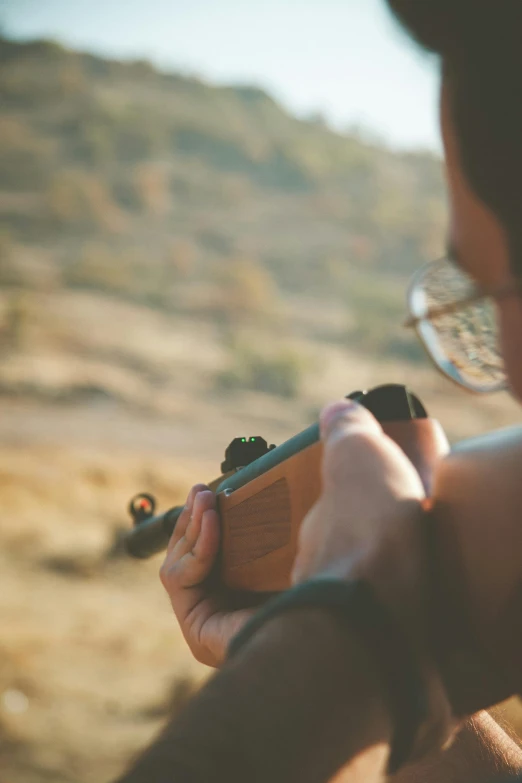 a man that is holding a gun in his hand, pexels contest winner, looking into the horizon, target reticles, relaxing, vintage color