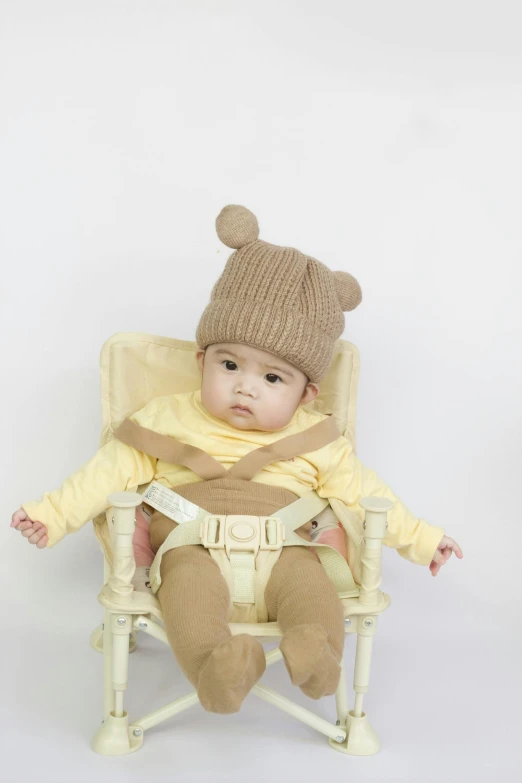 a baby sitting in a chair wearing a hat and scarf, instagram, mingei, official product photo, light brown, cute:2, body harness