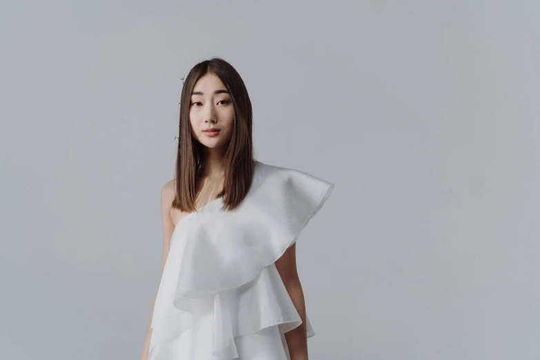 a woman in a white dress posing for a picture, inspired by Kim Tschang Yeul, trending on pexels, gutai group, white backdrop, frill, symetrical japanese pearl, shoulder-long straight