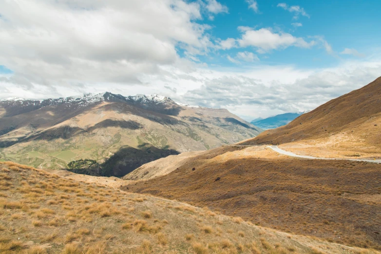 a view of the mountains from the top of a hill, by Peter Churcher, trending on unsplash, new zeeland, brown, head down, conde nast traveler photo