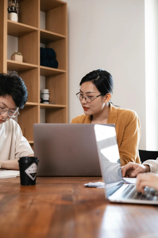 a group of people sitting around a table with laptops, by Jang Seung-eop, trending on unsplash, medium shot of two characters, high quality photo, asian female, programming