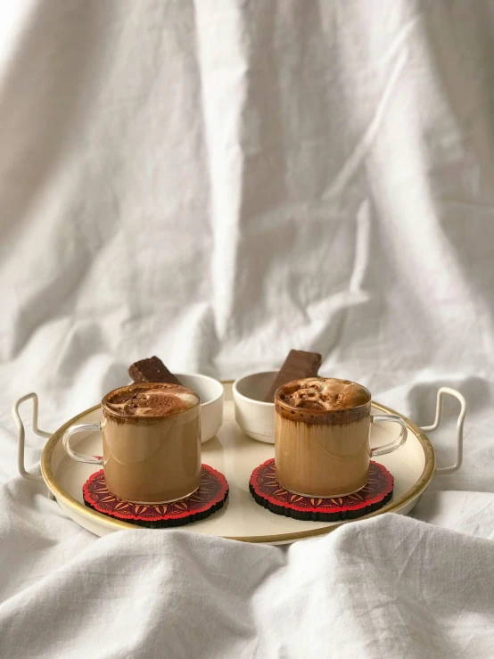 two cups of coffee on a tray on a bed, by Emma Andijewska, fully chocolate, maple syrup & hot fudge, - 9, colombian