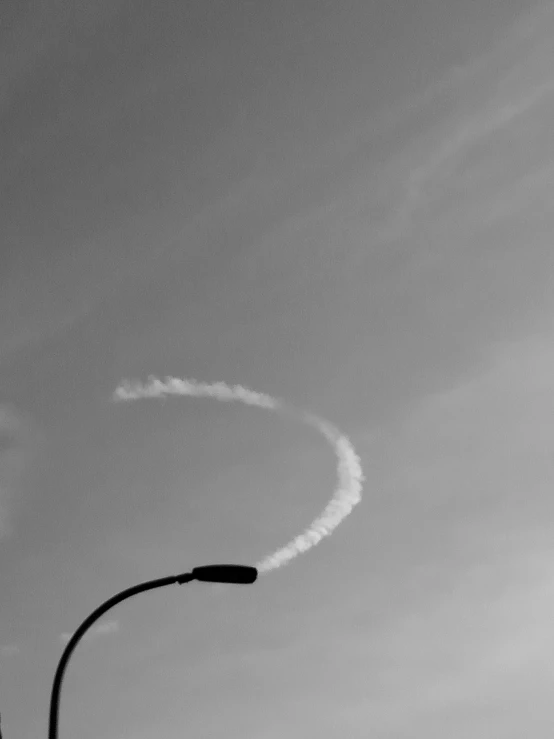 a black and white photo of a smoke trail in the sky, a black and white photo, inspired by André Kertész, postminimalism, curved red arrow, concrete poetry, bright halo, aerodynamic!!!!!!