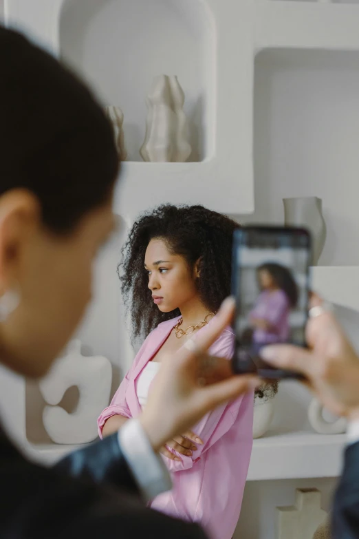 a woman taking a picture of herself in a mirror, trending on pexels, visual art, mixed-race woman, at a fashion shoot, serious business, medium shot of two characters