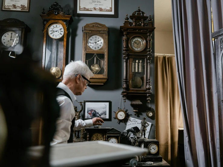 a man standing in front of a bunch of clocks, a portrait, pexels contest winner, arts and crafts movement, old man doing hard work, interior of a victorian house, profile image, watch photo