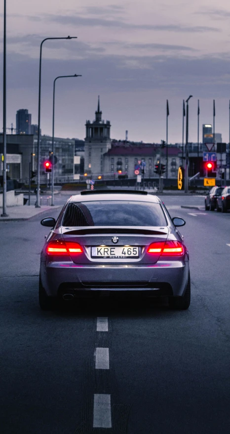 a car driving down a street next to a traffic light, by Adam Marczyński, pexels contest winner, bmw, back arched, low quality photo, thumbnail