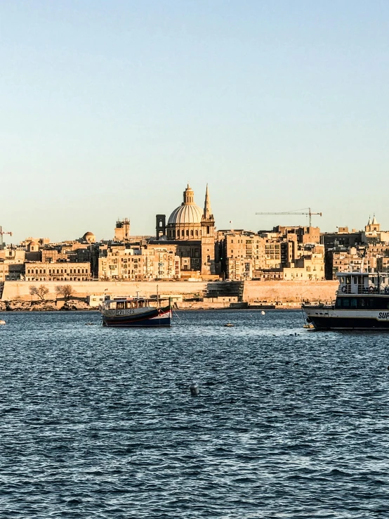 a large body of water with a city in the background, by Tom Wänerstrand, pexels contest winner, black domes and spires, med bay, late afternoon sun, panoramic