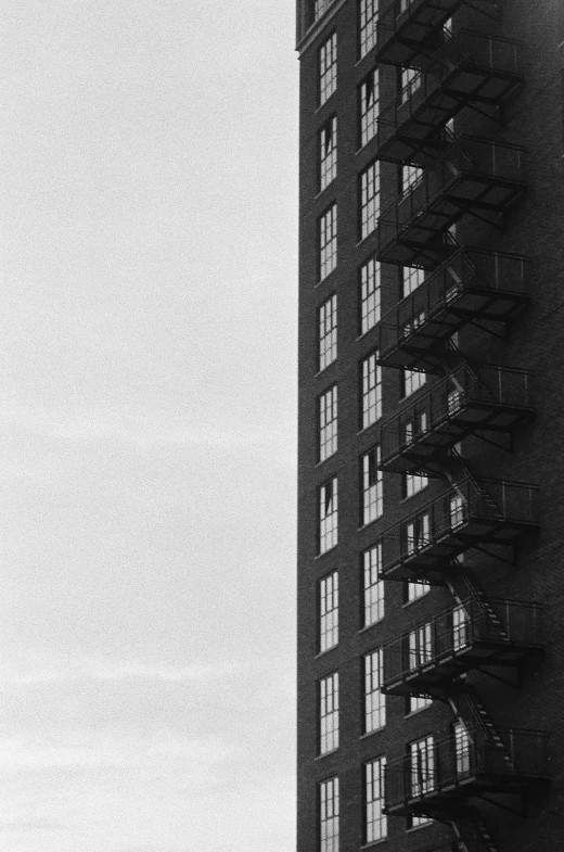 a black and white photo of a tall building, inspired by André Kertész, ( ( photograph ) ), diptych, fire escapes, ffffound