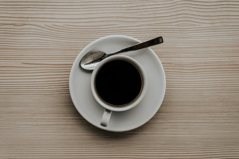 a cup of coffee and a spoon on a table, pexels contest winner, minimalism, dark angel of coffee, white, small, a wooden