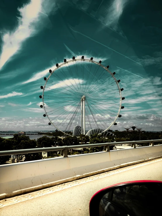 a large ferris wheel sitting on top of a bridge, set on singaporean aesthetic, viewed through the cars window, eyelevel!!! view!!! photography, 🚿🗝📝