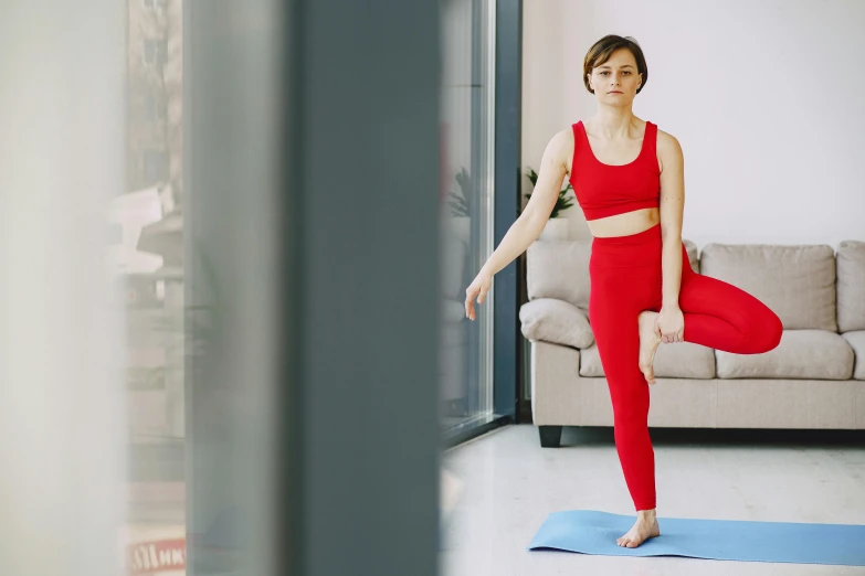 a woman doing a yoga pose in a living room, pexels contest winner, arabesque, red sport clothing, low quality footage, full body picture, ad image