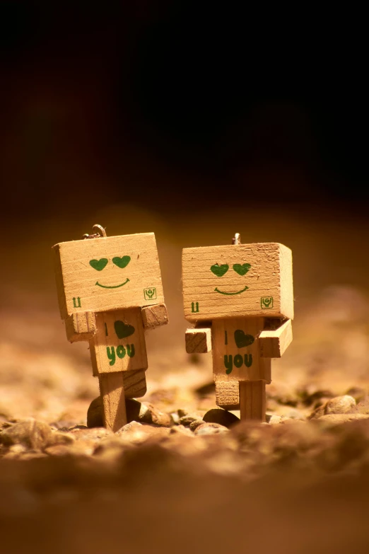 a couple of wooden figurines standing next to each other, a picture, unsplash, graffiti, adorable friendly robot, sepia photography, cubic, i love you