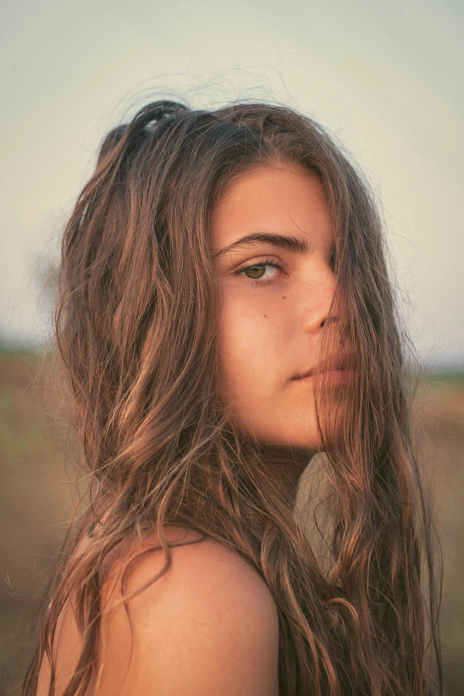 a woman with long hair standing in a field, a colorized photo, inspired by Elsa Bleda, trending on unsplash, close-up perfect face, hair : long brown, tanned, 18 years old