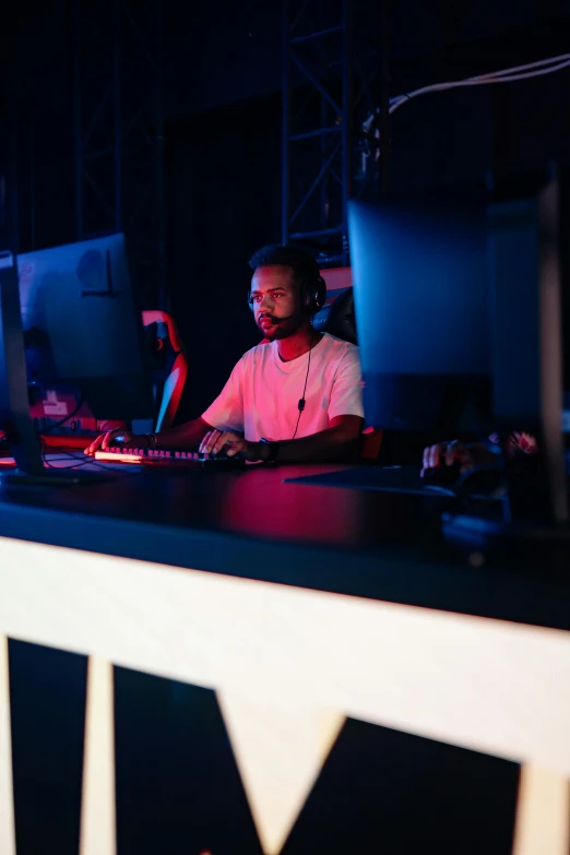 a man sitting at a desk in front of a computer, esports, in a nightclub, riyahd cassiem, high quality photo